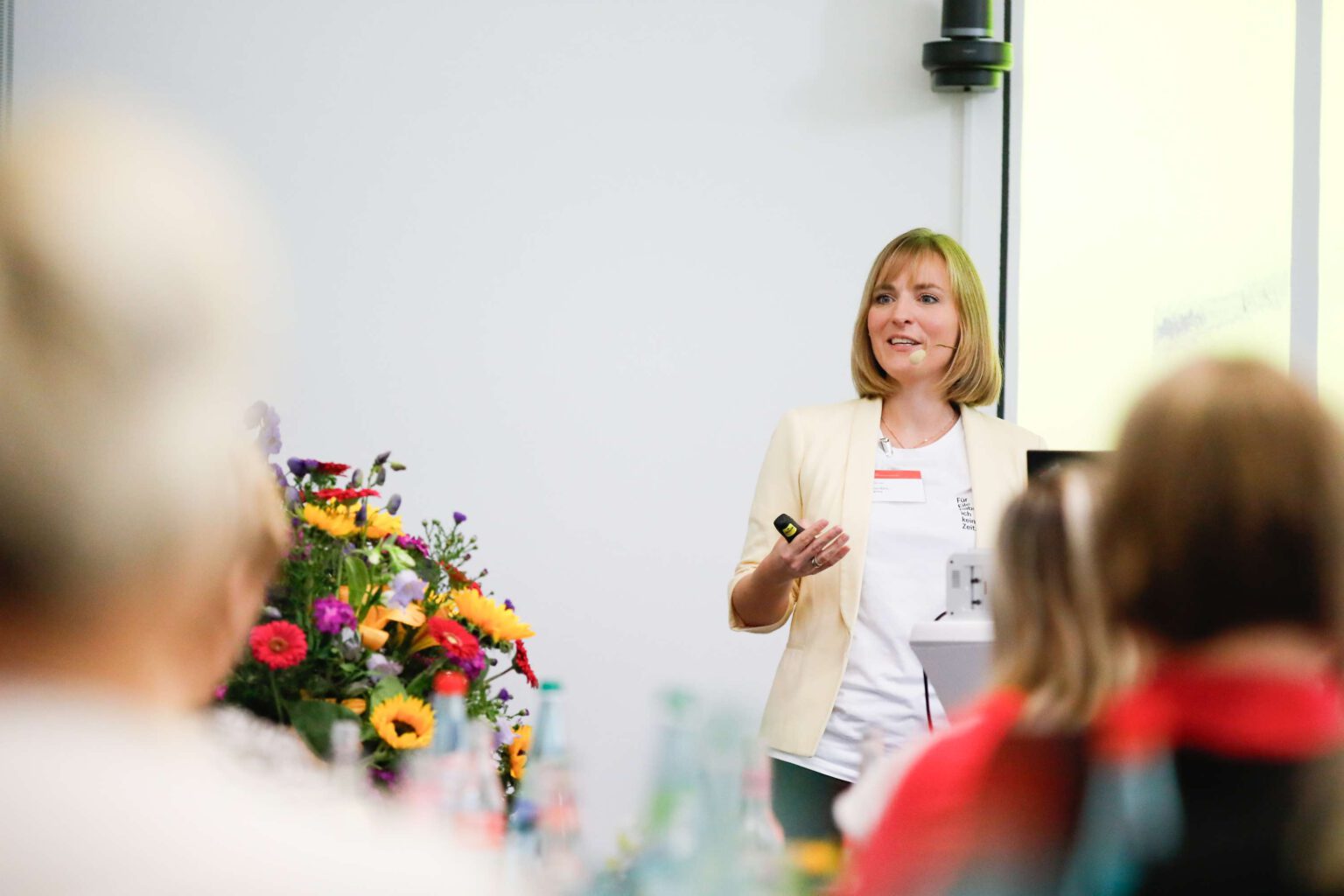 Eine Frau haelt einen Workshop ueber Resilienz vor einer Gruppe von Teilnehmern.